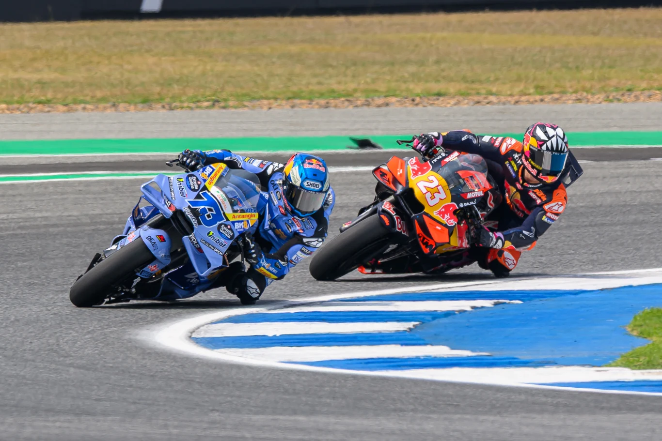 Rusza sezon 2026 MotoGP. Pierwszy wyścig odbędzie się w Tajlandii już w ten weekend. Dwóch motocyklistów ściga się na torze asfaltowym, jadąc w głębokim nachyleniu w zakręcie, na tle wyraźnych oznaczeń toru i zieleni w tle.