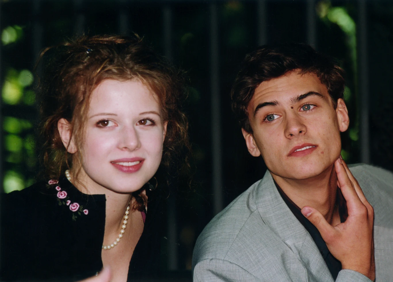 Karolina Gruszka i Mateusz Damięcki podczas konferencji filmu "Przedwiośnie" Młoda kobieta z jasną cerą i kasztanowymi włosami oraz młody mężczyzna w jasnej marynarce siedzą obok siebie, patrząc w różne strony, z naturalnym wyrazem twarzy, w tle rozmyte zielone elementy.