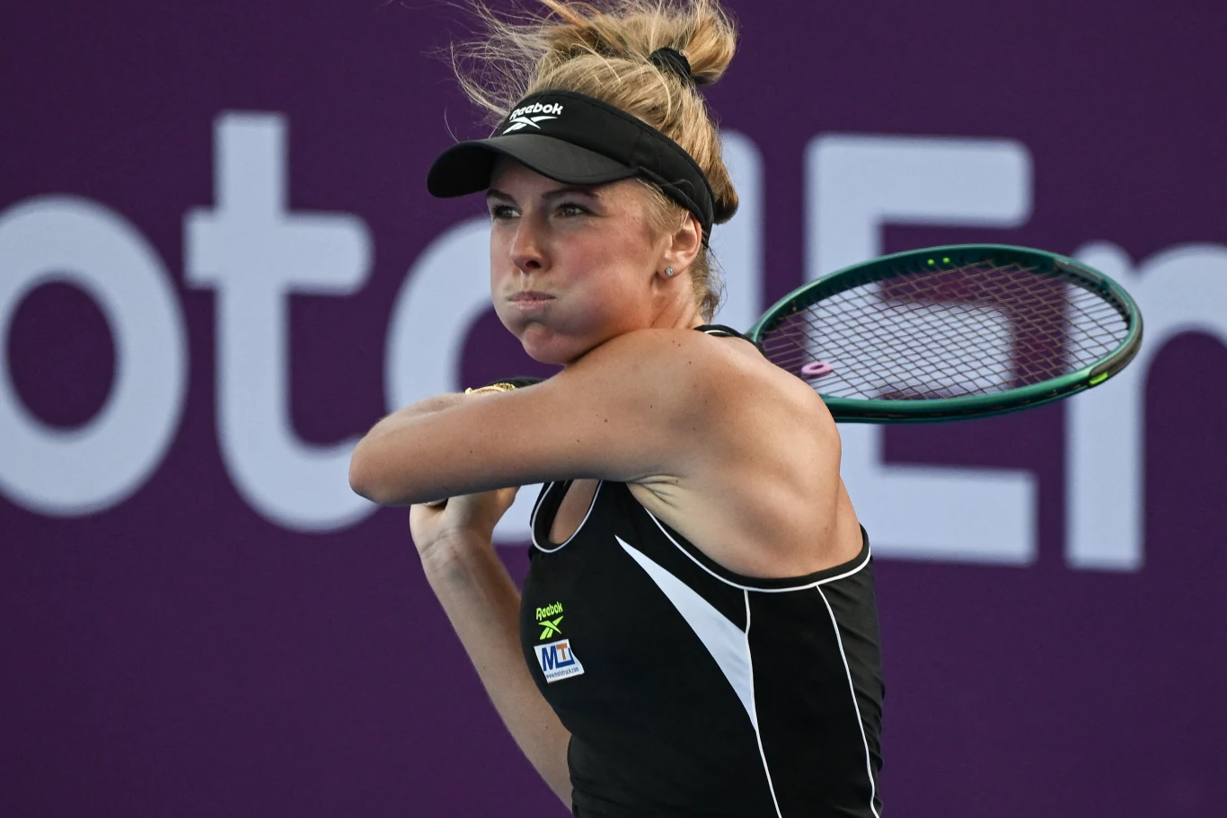 Magdalena Fręch rywalizowała o tytuł WTA 500 w Meridzie Tenisistka w czarnej sportowej sukience i czapce z daszkiem podczas intensywnej wymiany na korcie, skupiona, z rakietą uniesioną do uderzenia, na tle fioletowej ściany z rozmytym napisem.