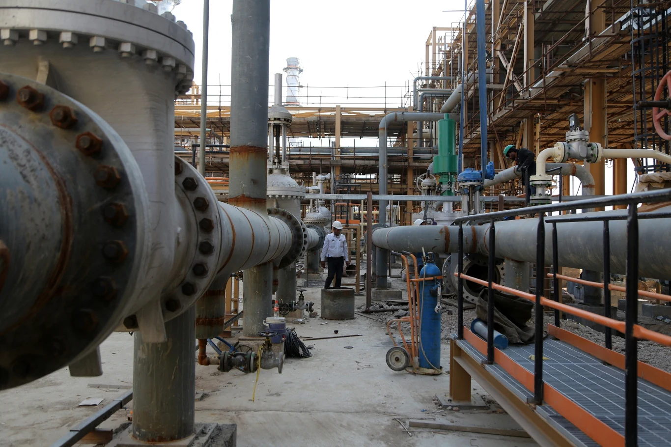 W Isfahanie znajduje się jedna z największych rafinerii w Iranie Kompleks przemysłowy z dużymi rurami i instalacjami technologicznymi, widocznymi elementami stalowej konstrukcji oraz osobą w kasku ochronnym, która sprawdza urządzenia.