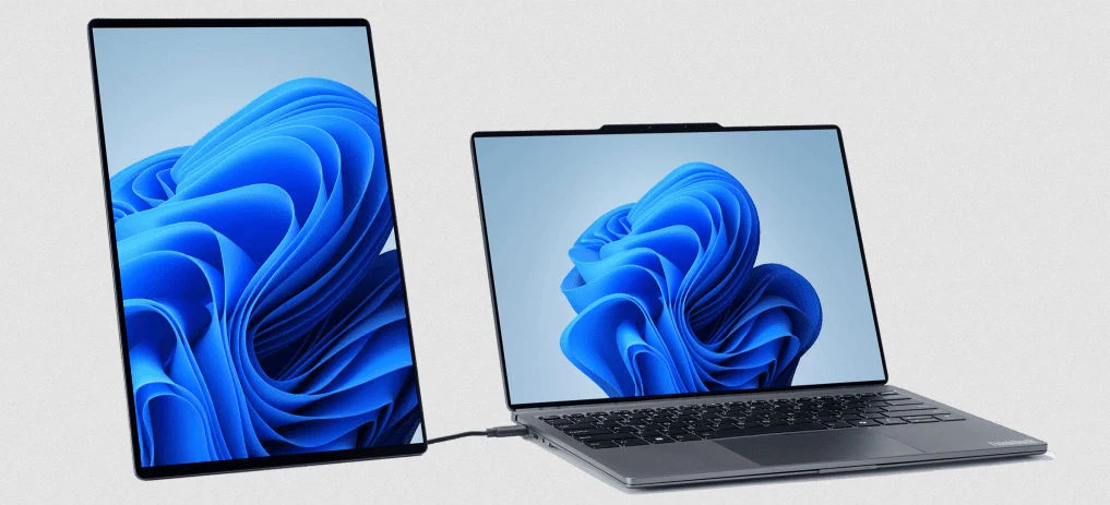 Lenovo ThinkBook Modular AI PC Concept ma wiele zastosowań. Laptop podłączony do zewnętrznego monitora o orientacji pionowej, oba ekrany wyświetlają ten sam motyw graficzny systemu Windows na jasnym tle.