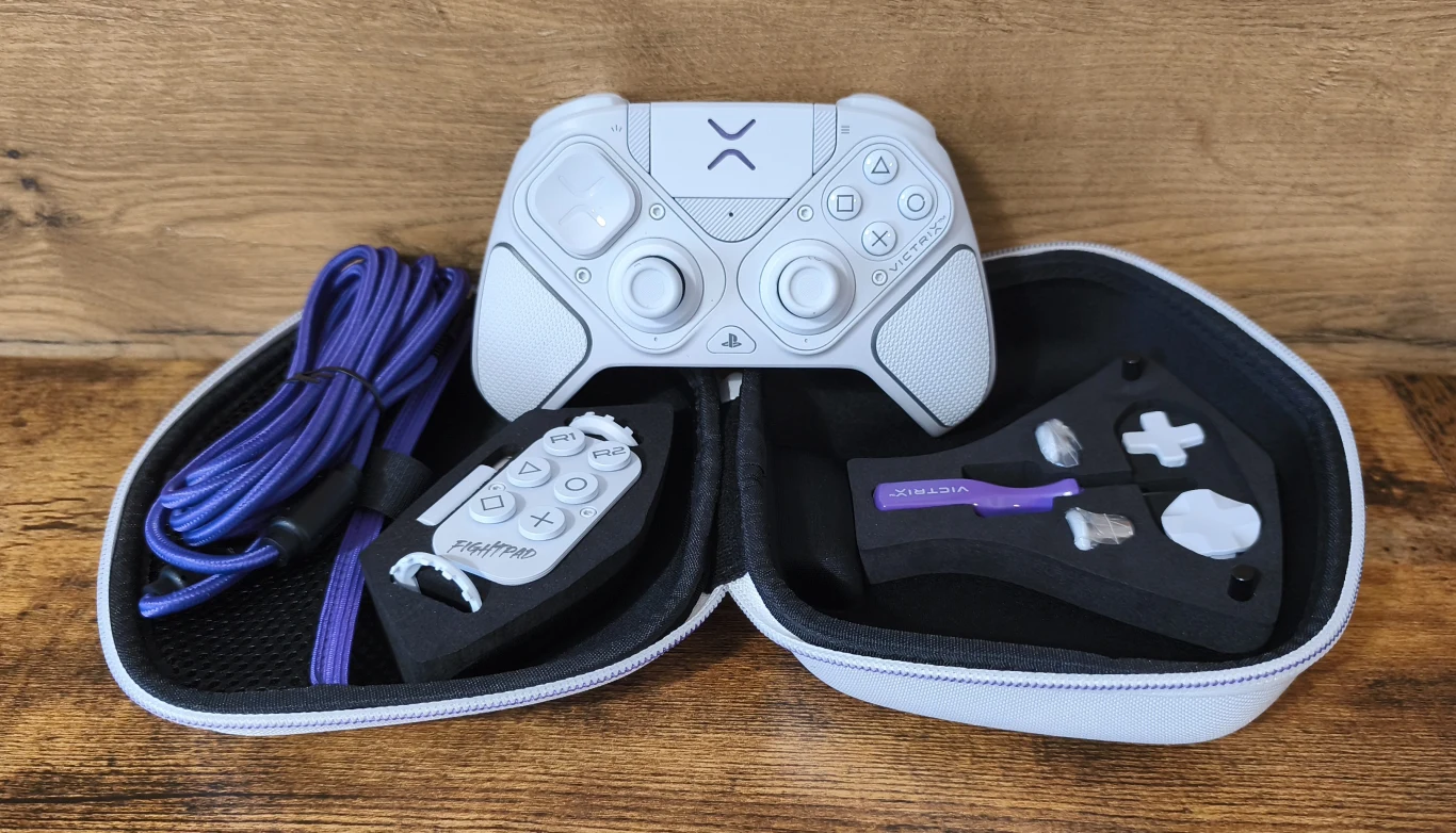 Biały kontroler do gier wraz z niebieskim przewodem USB, dodatkowymi przyciskami oraz elementami wymiennymi umieszczonymi w otwartym etui na drewnianym blacie.