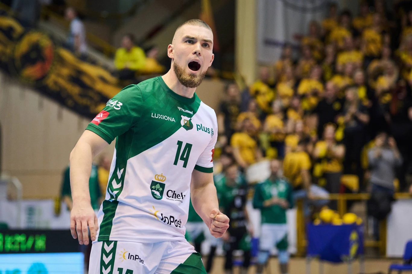 Jędrzej Goss został bohaterem spotkania Jędrzej Goss w zielono-białym stroju z numerem 14 podczas meczu, w tle kibice na żółto-czarnych trybunach.