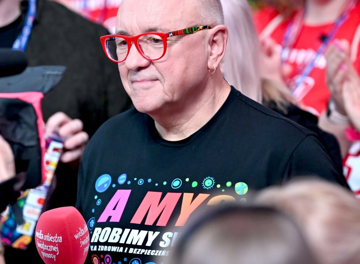 Pol'and'Rock ogłosił kolejnego wykonawcę Jurek Owsiak patrzy w tłum i trzyma mikrofon w ręku.