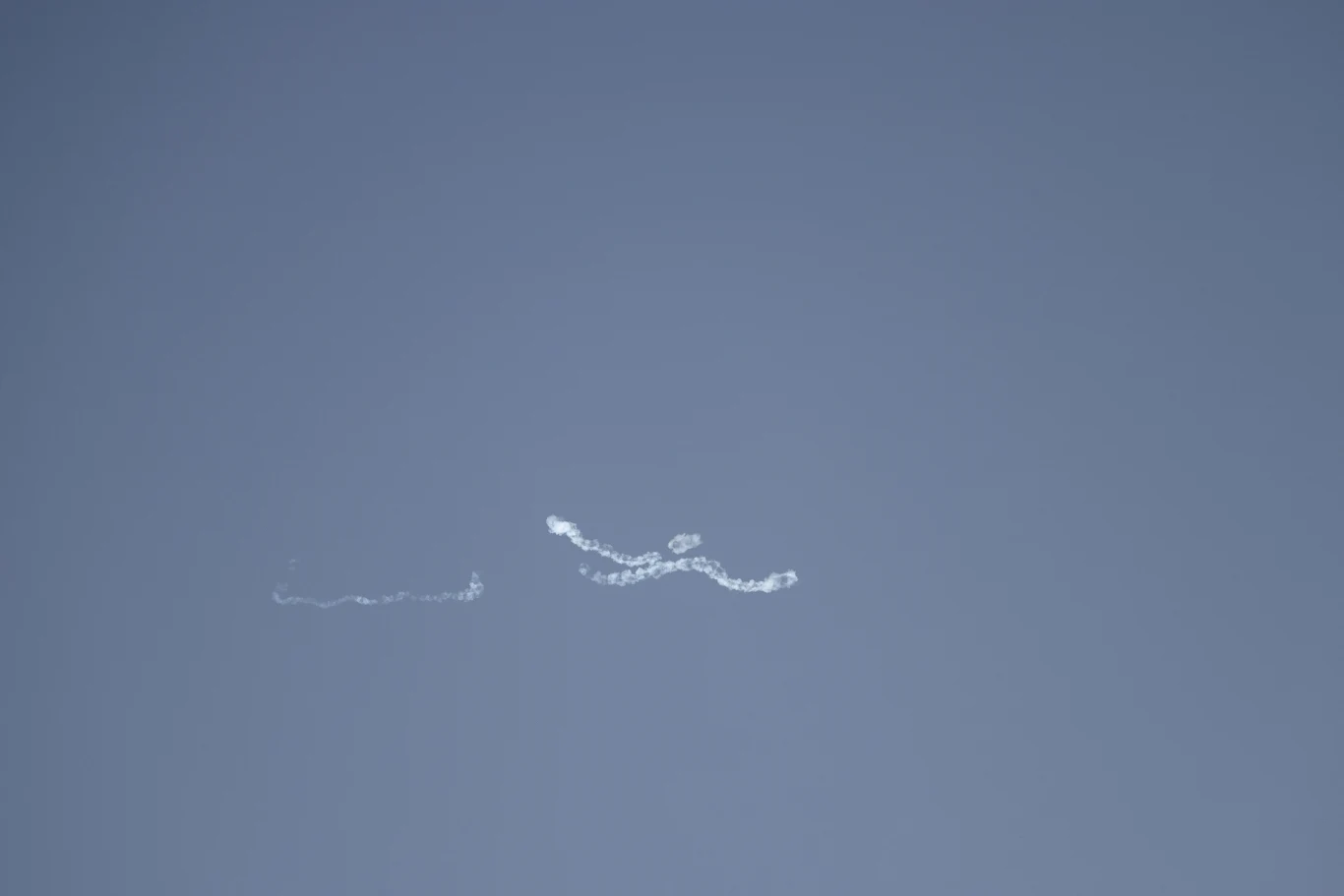 Nad Abu Zabi przechwytywane są irańskie drony Jasnoniebieskie niebo z dwoma cienkimi, falistymi smugami białego dymu unoszącymi się na tle czystej przestrzeni.