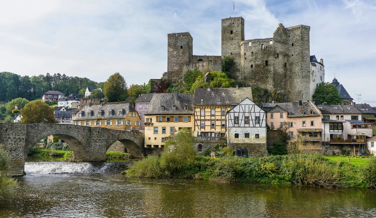 Z czego słynie zamek Runkel? Kamienny most nad rzeką Lahn prowadzi do średniowiecznego zamku Runkel z trzema wieżami i domami szachulcowymi.