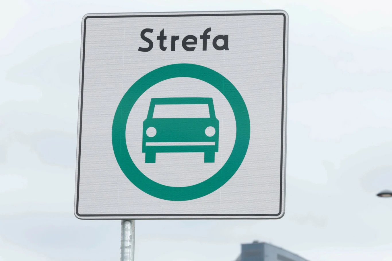 Władze Katowic przedstawiły założenia dotyczące Strefy Czystego Transportu. Biały znak drogowy z napisem „Strefa” i zielonym symbolem auta wskazujący Strefę Czystego Transportu w Katowicach.