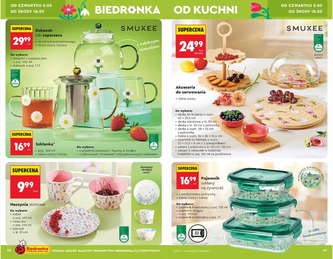 Zestaw porcelanowych naczyń kuchennych i szklanych akcesoriów do serwowania, w tym dzbanek, szklanki, pojemniki oraz talerze pod przykryciem, ozdobionych florystycznymi motywami, prezentowanych w aranżacji z owocami i deserami na tle jasnych blatów.