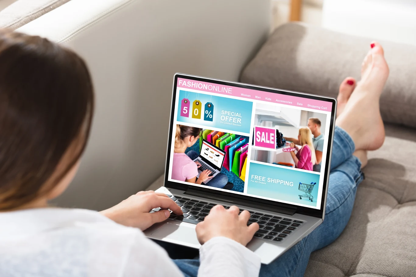 Osoba siedząca na kanapie przegląda internetowy sklep odzieżowy na laptopie, na ekranie widoczne oferty promocyjne, wyprzedaż oraz kolorowe ubrania.