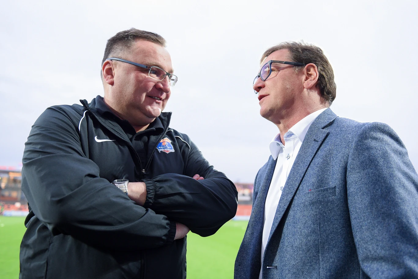 Czesław Michniewicz i Jan Urban Czesław Michniewicz i Jan Urban rozmawiają na murawie stadionu, jeden w kurtce sportowej, drugi w marynarce.