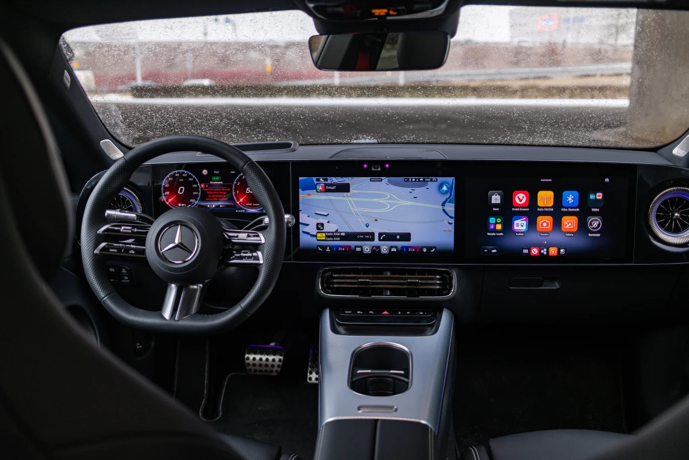 Wysoka jakość wykonania, intuicyjna obsługa, porządne materiały i mnóstwo pikseli - oto wnętrze CLA. Luksusowe wnętrze samochodu marki Mercedes z dużym ekranem systemu multimedialnego na środku deski rozdzielczej, cyfrowym zestawem wskaźników za kierownicą oraz sportową kierownicą z logotypem Mercedes-Benz.