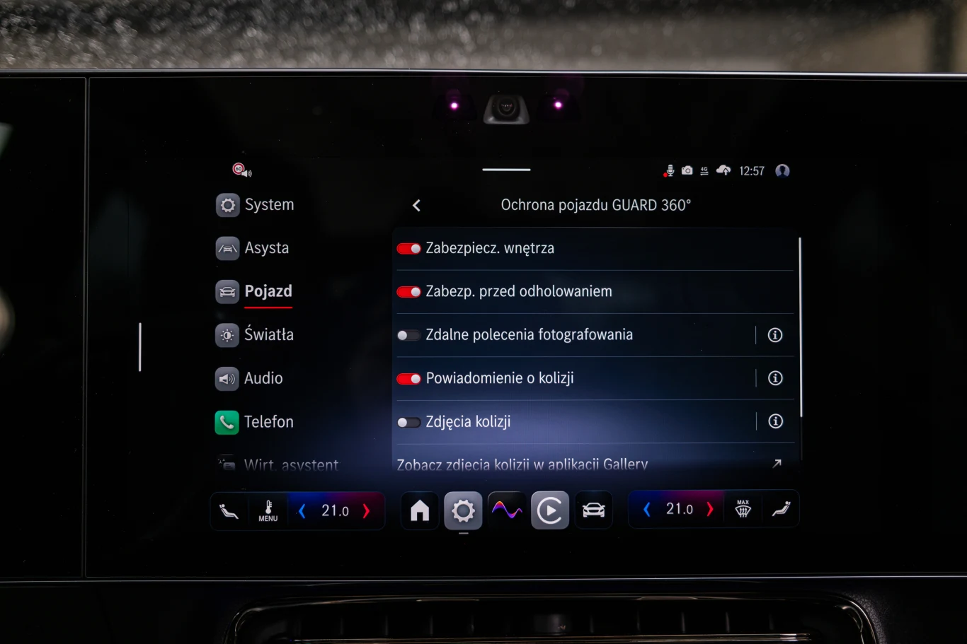 Szeroki parasol systemów ochrony zawiera między innymi ten, który powiadomi właściciela o kolizji czy automatycznie zapisze zdjęcia z wypadku. Wyświetlacz systemu multimedialnego samochodu pokazujący ustawienia ochrony pojazdu GUARD 360°, z aktywowanymi opcjami zabezpieczenia wnętrza, zabezpieczenia przed odholowaniem oraz powiadomienia o kolizji; widoczne również menu boczne z ikonami funkcj...
