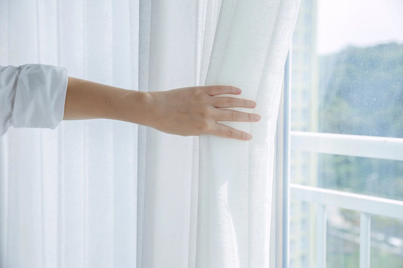 Dodaj do pralki podczas prania firanek. Zapomnisz o prasowaniu Dłoń chwytająca białe, niepogniecione firanki.