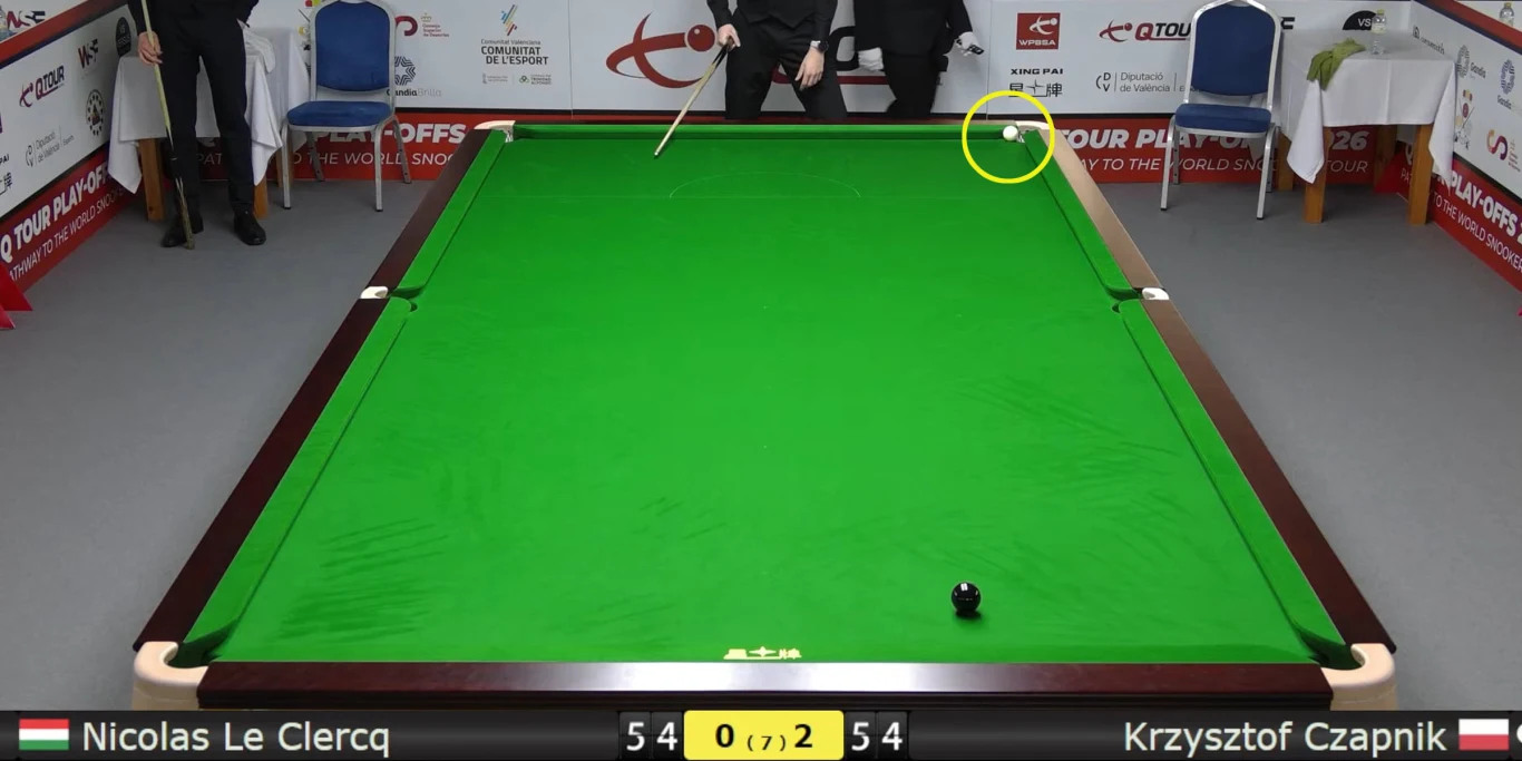 Snookerowy stół z jedną czarną bilą blisko dolnej bandy, zawodnik w ciemnym ubraniu wykonuje uderzenie białą bilą znajdującą się przy górnej bandzie; przy stole widoczne są akcesoria i krzesła, na dole ekranu pasek wyników z nazwiskami zawodników: Nico...