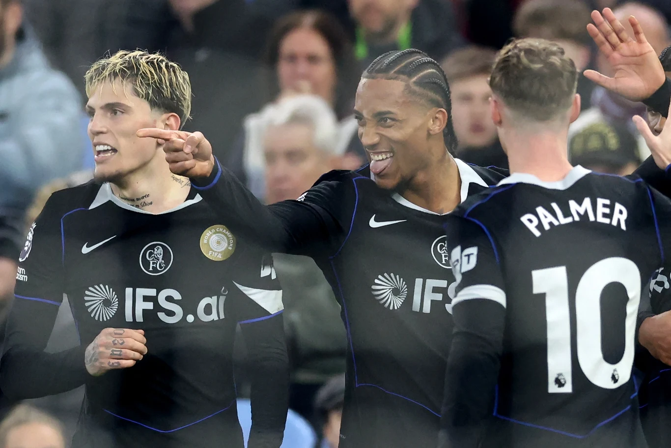 Trzech piłkarzy w czarnych strojach drużyny Chelsea świętuje bramkę podczas meczu, jeden z nich wskazuje palcem, pozostali wykazują radość; na koszulkach widoczne napisy sponsora IFS oraz nazwisko Palmer z numerem 10.