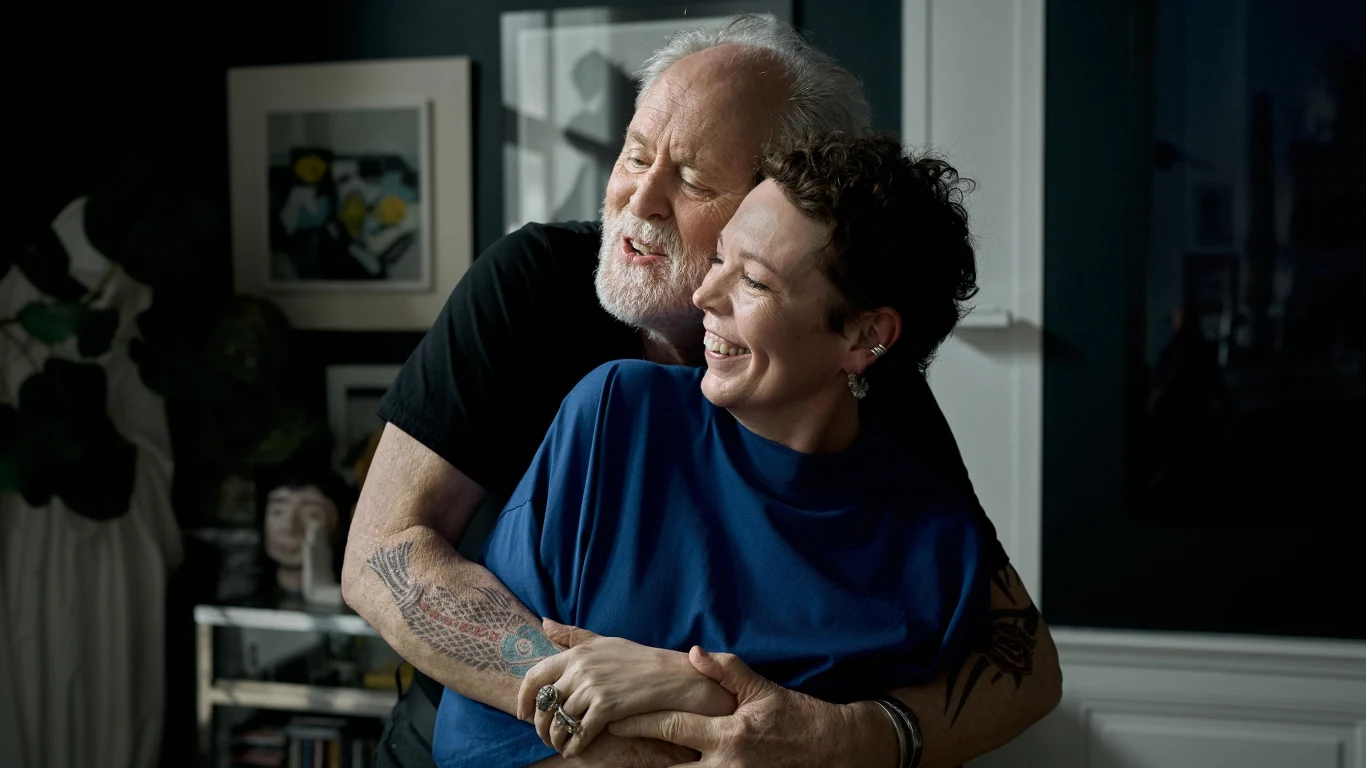 John Lithgow i Olivia Colman w scenie z filmu "Mów mi Jimpa" John Lithgow i Olivia Colman jako Jimpa i Hannah w filmie „Mów mi Jimpa” na tle nowoczesnej sztuki.