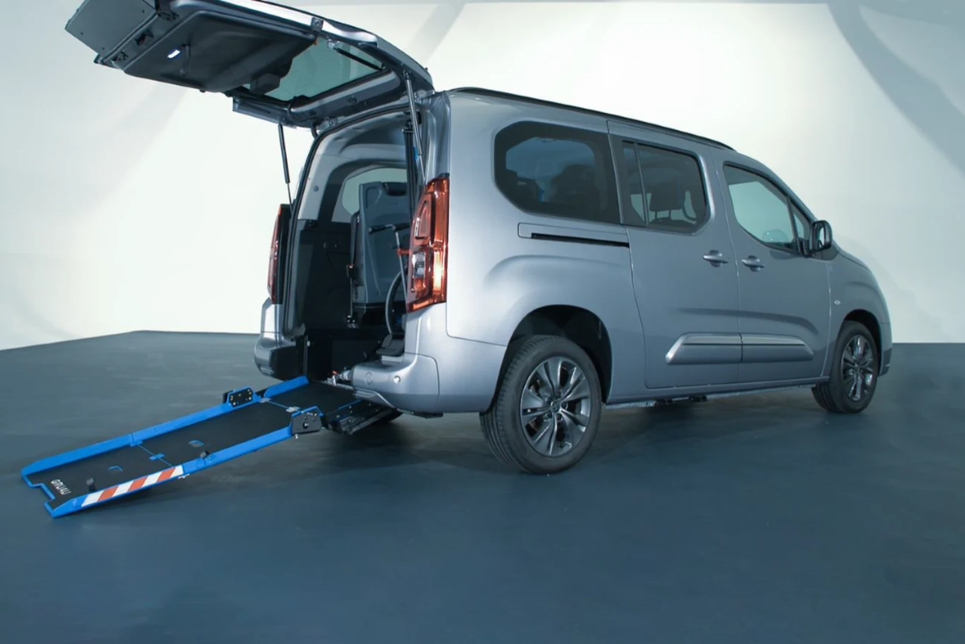 Nabór wniosków na dofinansowanie z Państwowego Funduszu Rehabilitacji Osób Niepełnosprawnych (PFRON) już ruszył. Srebrny samochód typu van z otwartą tylną klapą i wysuniętą rampą umożliwiającą wjazd wózka inwalidzkiego, przystosowany do przewozu osób z niepełnosprawnościami.