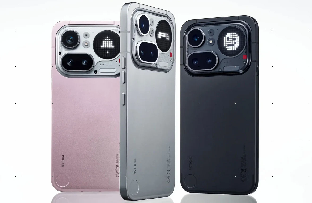 Smartfon Nothing Phone 4a Pro. Trzy nowoczesne smartfony w kolorach różowym, srebrnym i czarnym ustawione pionowo, każdy z dużym aparatem fotograficznym i okrągłym wyświetlaczem LED na tyle, wyświetlającym różne ikony z pikseli.