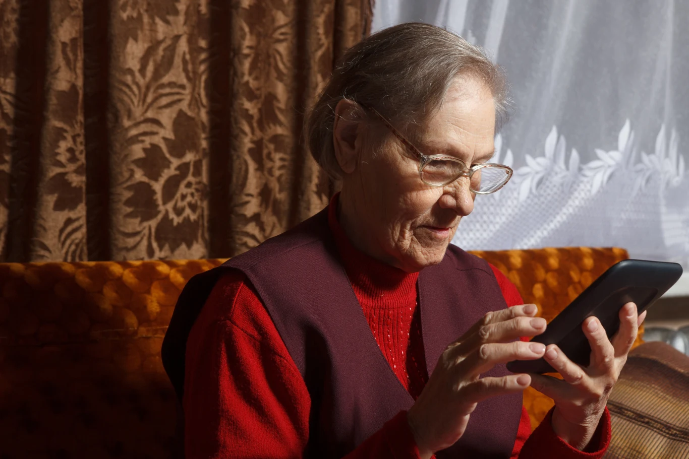 Wnioski do konkursu o mikrodotacje dla seniorów można składać od 1 września do 9 października br. Starsza kobieta w okularach siedzi na kanapie i korzysta z tabletu, skupiając się na ekranie urządzenia.