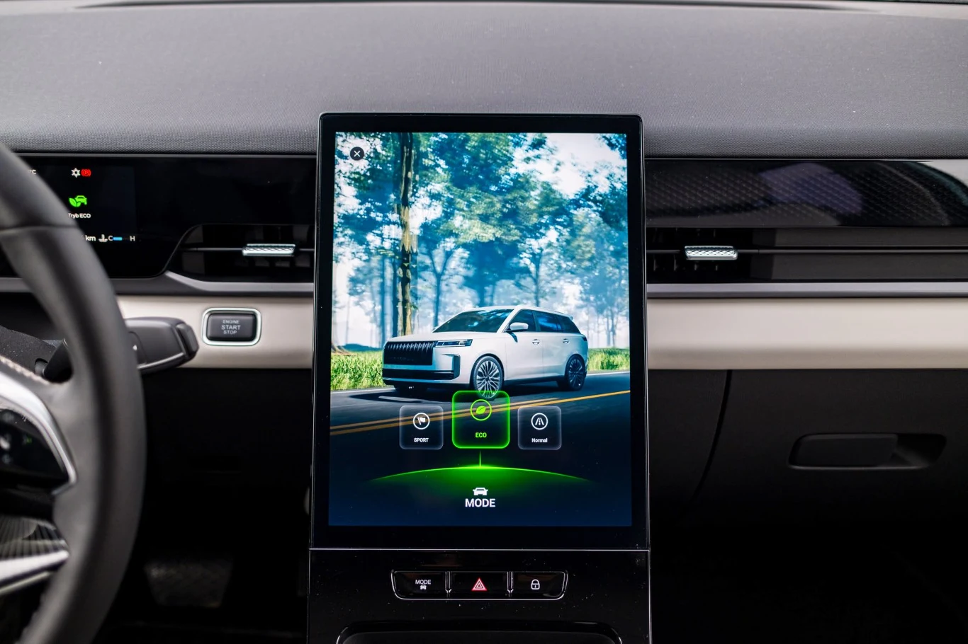 Duży pionowy ekran dotykowy na konsoli środkowej samochodu wyświetla obraz pojazdu w otoczeniu drzew, z aktywnym trybem SR MODE i ikonami do obsługi systemów pokładowych.