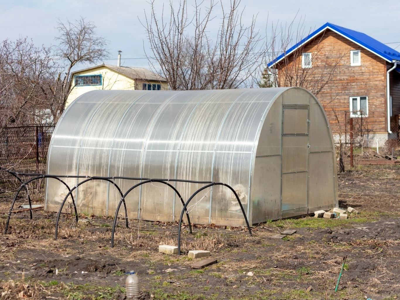 Szklarnia o półkolistym kształcie ustawiona na działce. 
