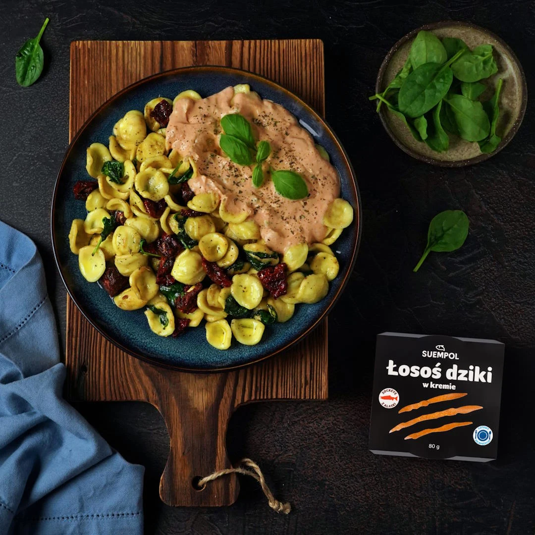 Gdy szpinak zwiędnie, dodajemy na patelnię śmietanę oraz łososia w kremie 