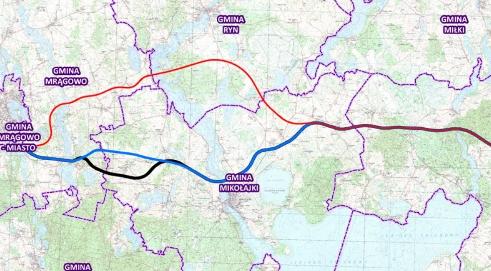 Mapa z wielokolorowymi trasami oznaczającymi różne warianty przebiegu ulic lub dróg przez tereny gmin Mrągowo, Mikołajki, Ryn i okolic, z wyraźnie zaznaczonymi granicami administracyjnymi tych gmin.