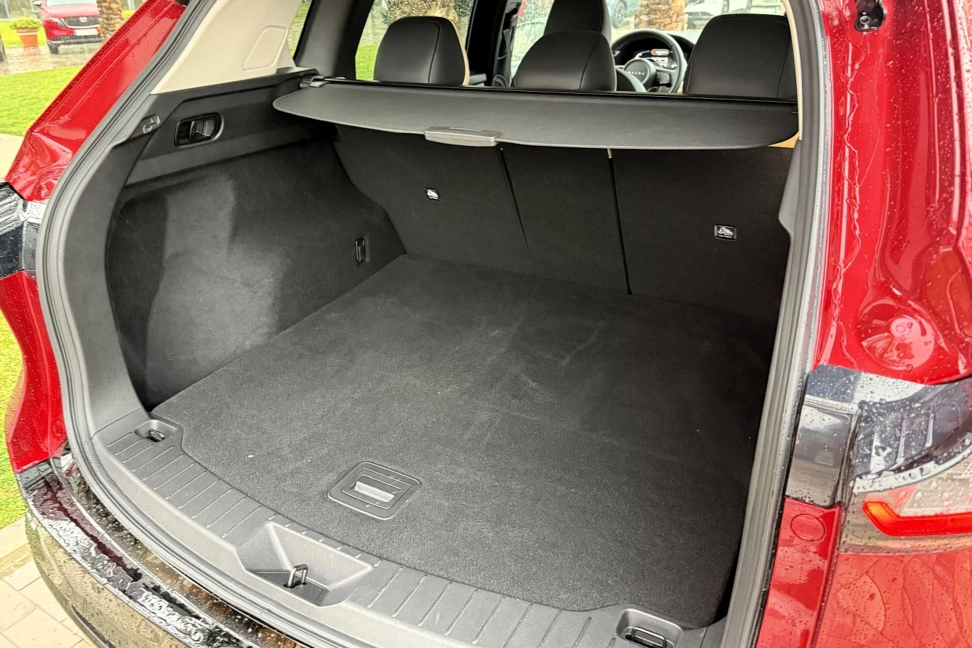 Obszerna, czysta przestrzeń bagażnika samochodu typu SUV z rozłożoną półką i widocznymi trzema tylnymi zagłówkami foteli pasażerów.