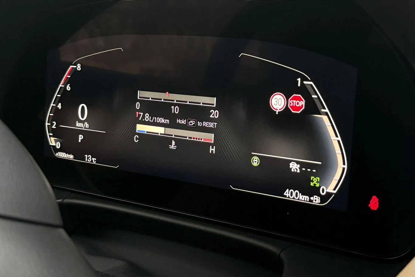 Cyfrowy wyświetlacz samochodu z prędkościomierzem, informacją o średnim zużyciu paliwa 7,8 l/100 km, ostrzeżeniami o znakach drogowych ograniczenia prędkości do 30 km/h i stop, symbolem ostrzegawczym oraz wskaźnikami przebiegu, temperatury i poziomu pa...