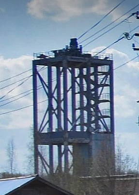 Jedna z wybudowanych przez Rosję wież Wysoka metalowa konstrukcja przemysłowa z kratownicą, na szczycie której znajdują się urządzenia techniczne, otoczona liniami energetycznymi, w tle niebo z chmurami.