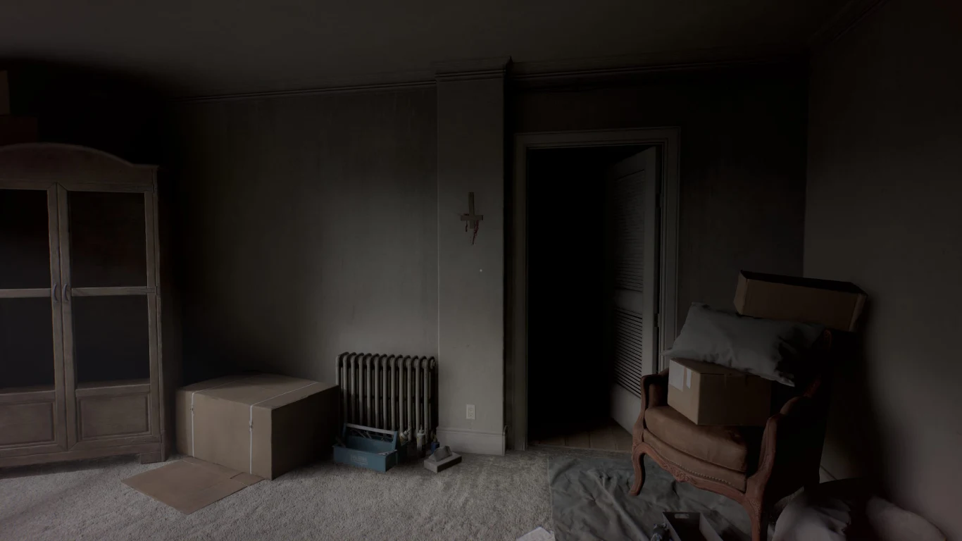 Zaniedbany pokój z przygaszonym światłem, w którym znajduje się stara szafa, grzejnik i kartony ustawione po lewej stronie, a po prawej brązowy fotel obłożony poduszkami i pudłami, naprzeciwko otwartych drzwi prowadzących do ciemnego pomieszczenia.
