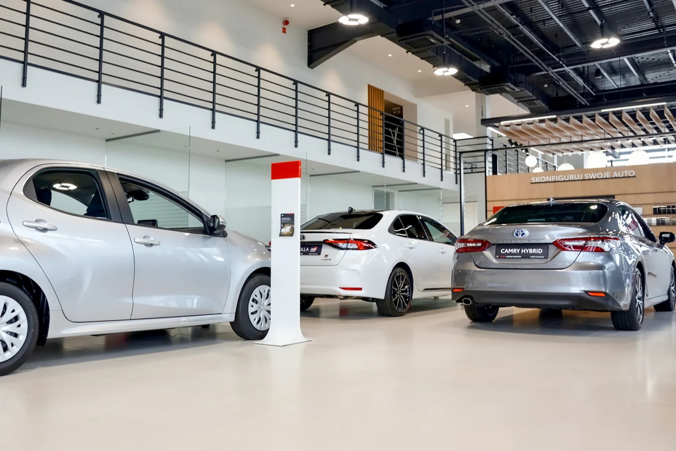 Przedłużający się konflikt w Iranie może odbić się na kondycji branży motoryzacyjnej Trzy samochody osobowe, dwa srebrne i jeden biały, w salonie z jasną podłogą i przeszklonym balkonem.