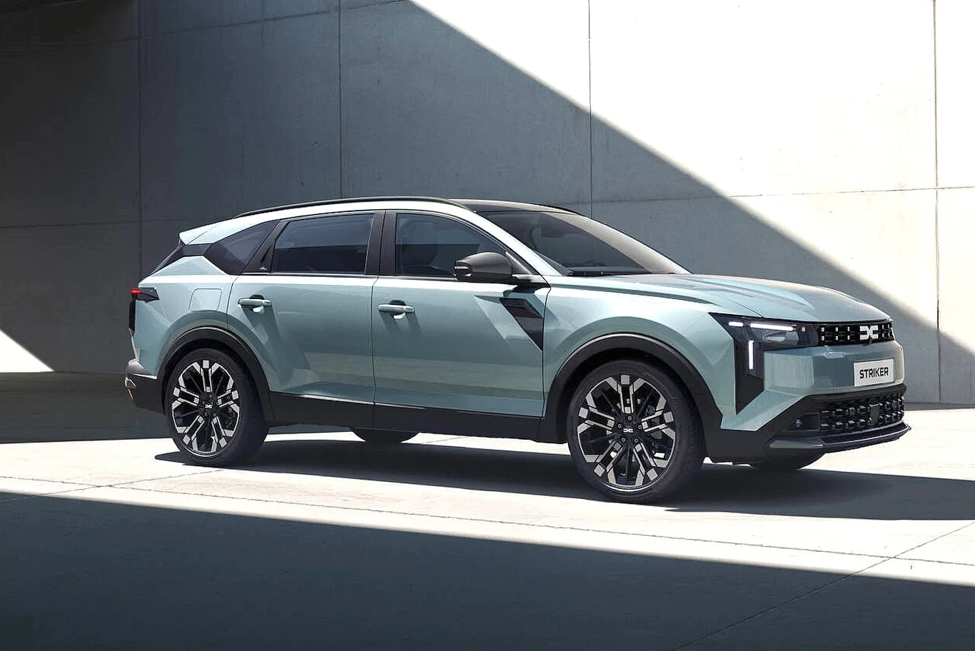 Nowoczesny SUV w kolorze jasnoniebieskim z czarnymi elementami nadwozia stoi na tle betonowej ściany, w dobrze oświetlonym miejscu, podkreślając muskularne linie i atrakcyjność designu pojazdu.