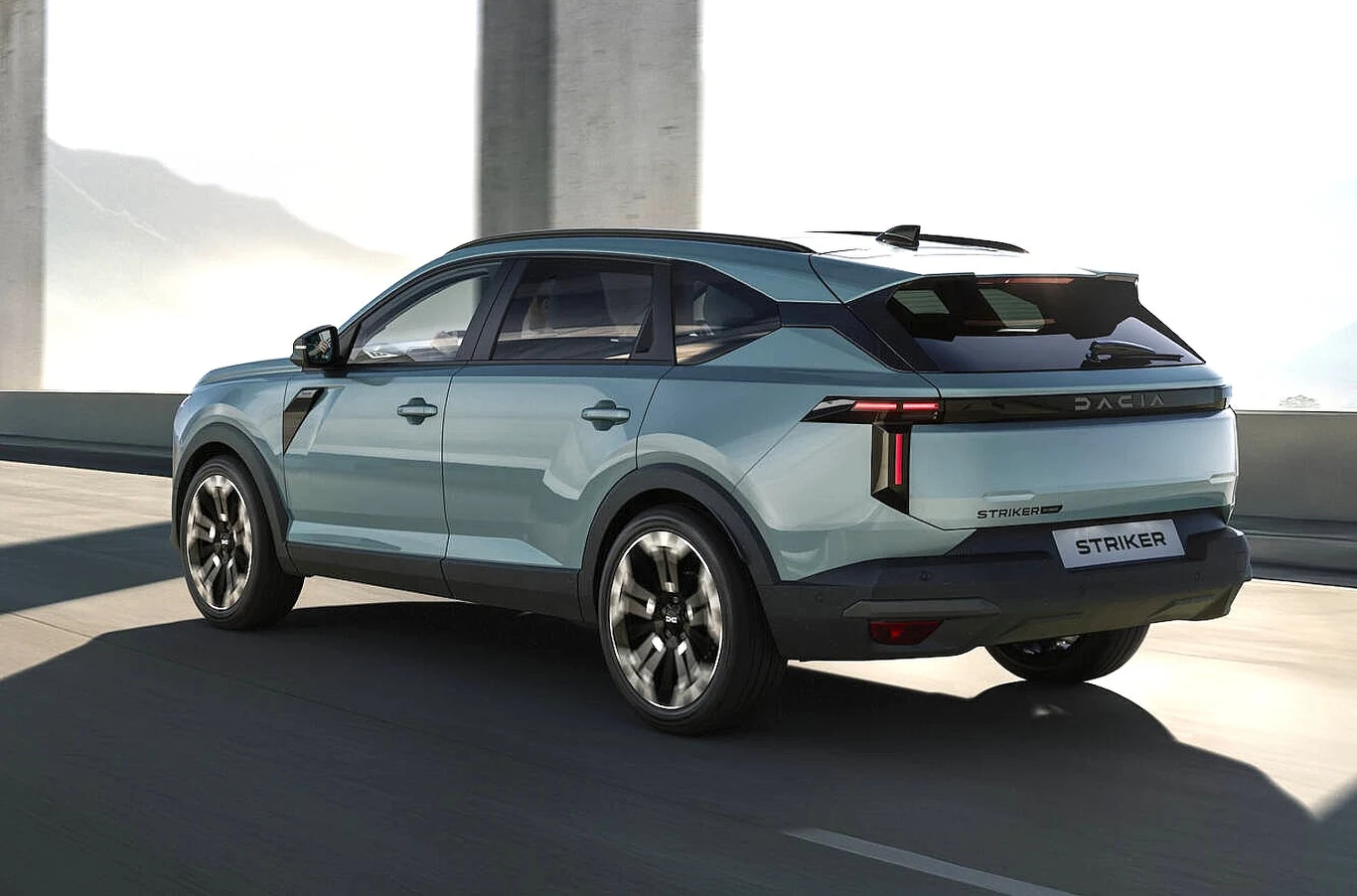 Jasnoniebieski SUV Dacia o nowoczesnym, dynamicznym designie, przyciemnianych szybach i dużych aluminiowych felgach jedzie po szerokiej, słonecznej drodze z betonowymi filarami w tle.