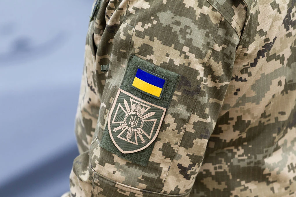 Mundur ukraińskiego żołnierza w kamuflażu z naszywką flagi i emblematem trójzęba, zdjęcie ilustracyjne.