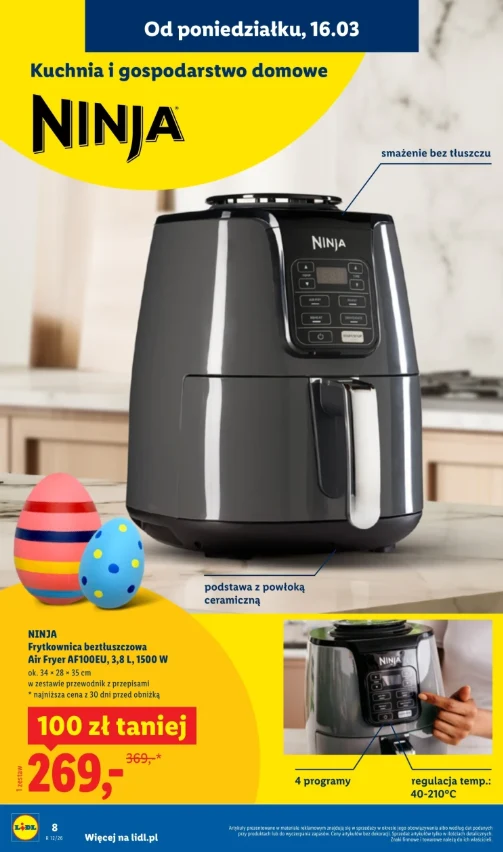 Duża czarna beztłuszczowa frytkownica marki Ninja z cyfrowym panelem sterowania ustawiona na kuchennym blacie, obok kolorowych pisanek wielkanocnych; widoczne wyróżnienia takie jak ceramiczna powłoka podstawy, smaczne potrawy bez tłuszczu, 4 programy g...