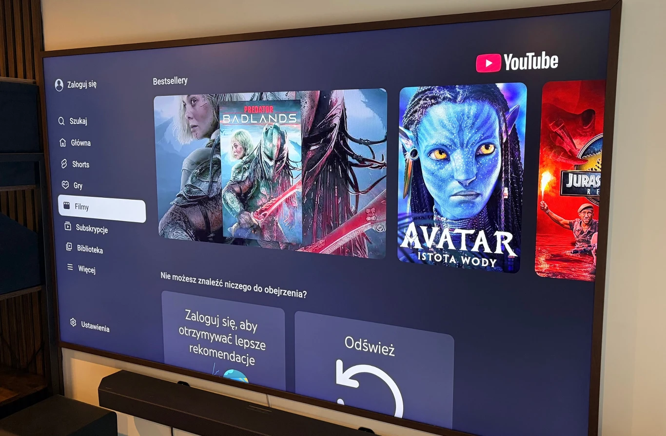 YouTube wprowadza długie reklamy, których nie da się pominąć. Ekran telewizora z aplikacją YouTube, widoczne kategorie oraz plakaty filmów.