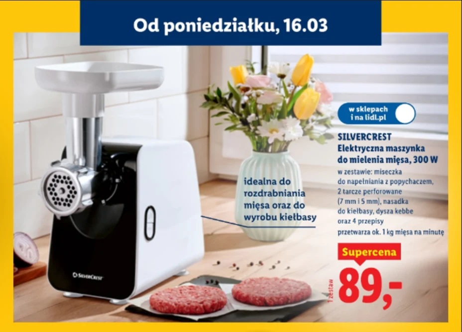 Elektryczna maszynka do mielenia mięsa ustawiona na kuchennym blacie obok talerza z dwoma kotletami mielonymi oraz wazonu z kolorowymi kwiatami; na zdjęciu widoczna także oferta promocyjna i opis produktu wraz z ceną 89 zł.