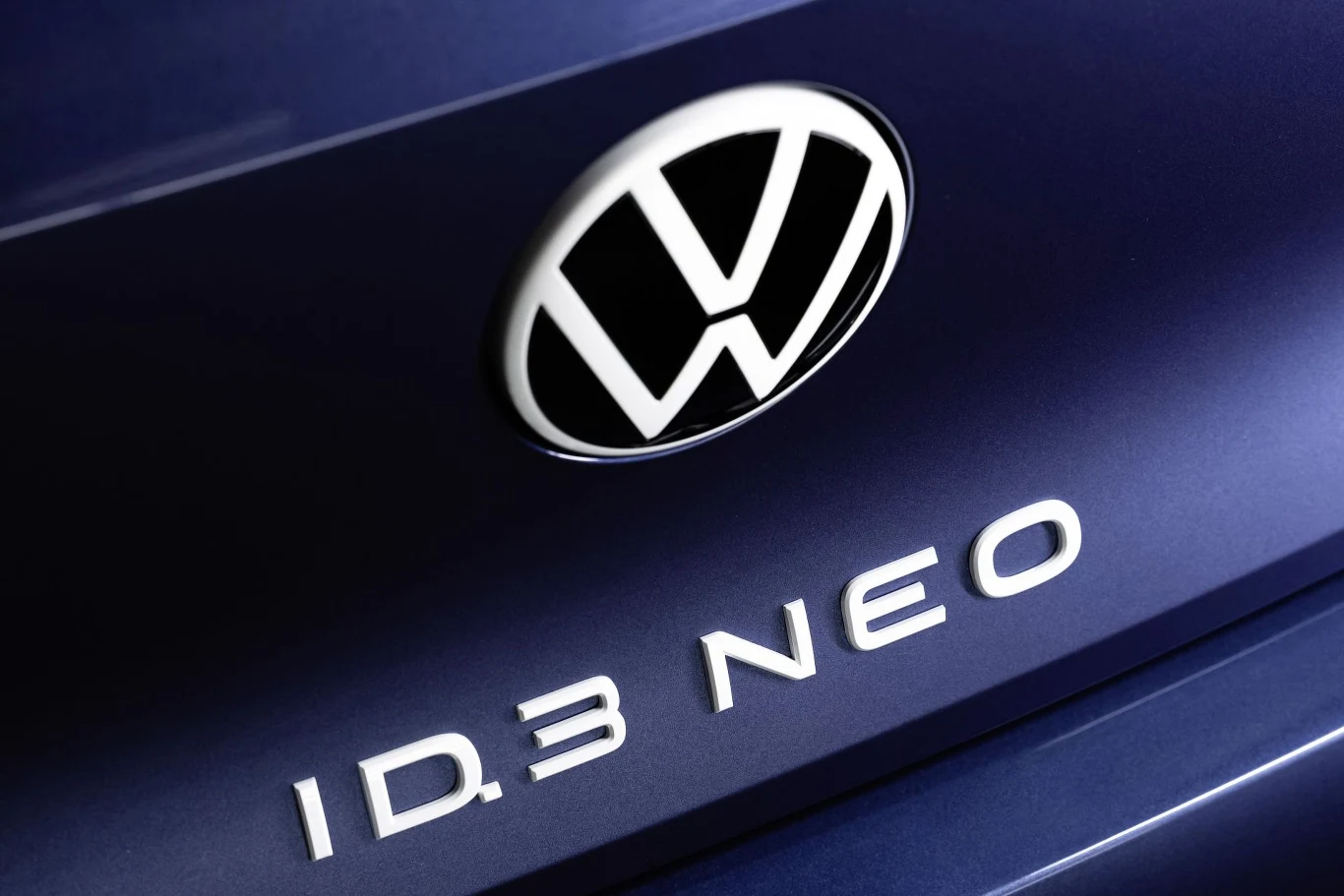 Ciemnoniebieska karoseria samochodu z dużym logotypem Volkswagena oraz napisem ID.3 NEO w chromowanym wykończeniu.