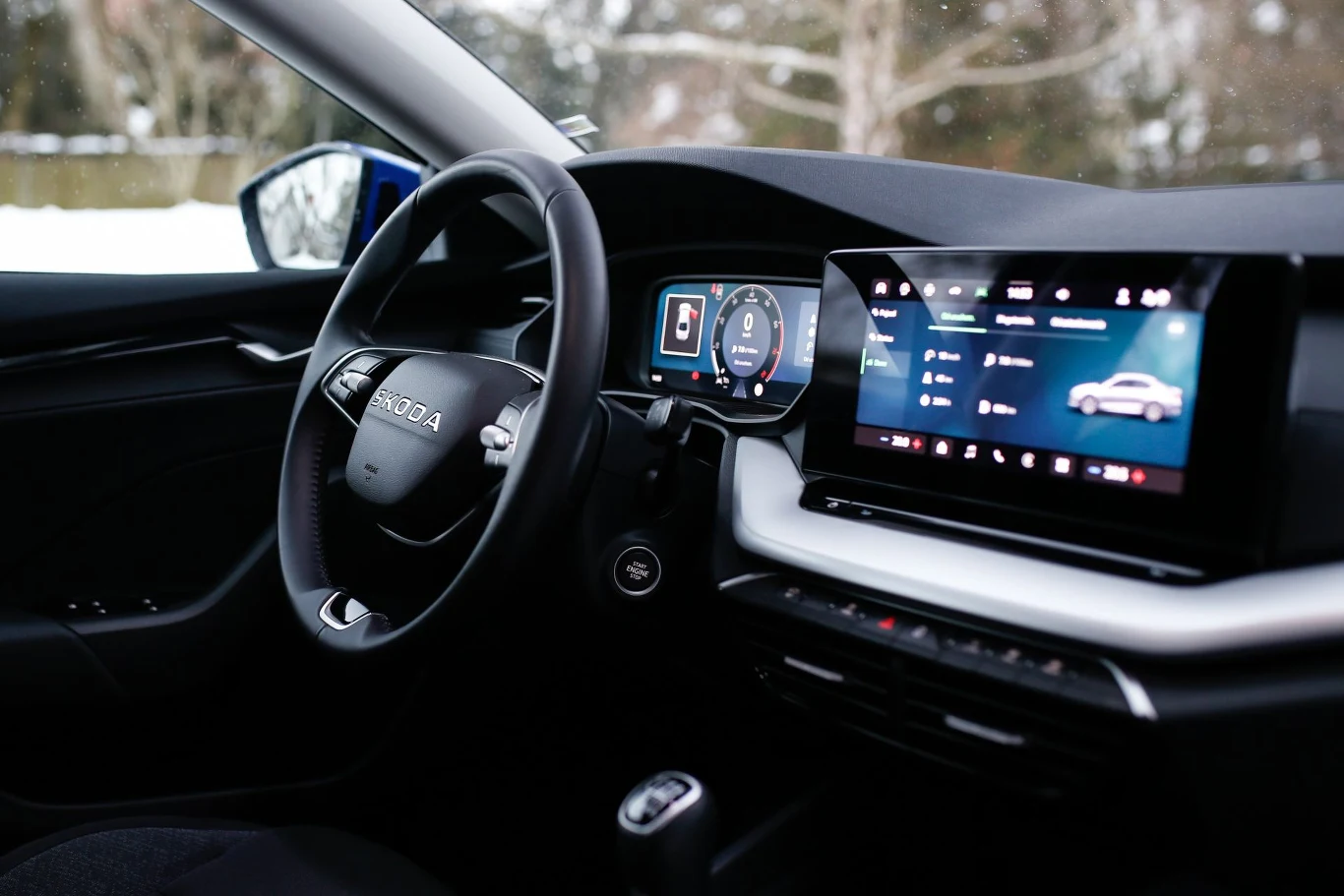Nowoczesne wnętrze samochodu marki Skoda z cyfrowym kokpitem, wielofunkcyjną kierownicą oraz dużym dotykowym ekranem centralnym wyświetlającym system multimedialny.