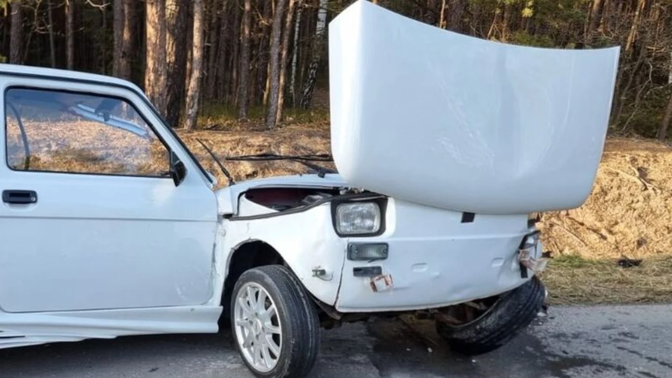 Uszkodzony biały fiat z odgiętą maską na poboczu drogi w otoczeniu drzew i nasypu, po wypadku w Lubelskiem.