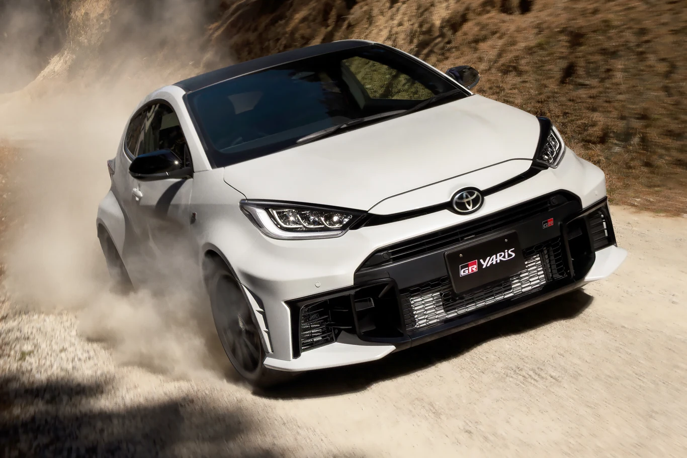 Toyota GR Yaris po kolejnych modyfikacjach. Dynamic oraz Aero Performance Biała Toyota GR Yaris pędzi po szutrowej drodze.