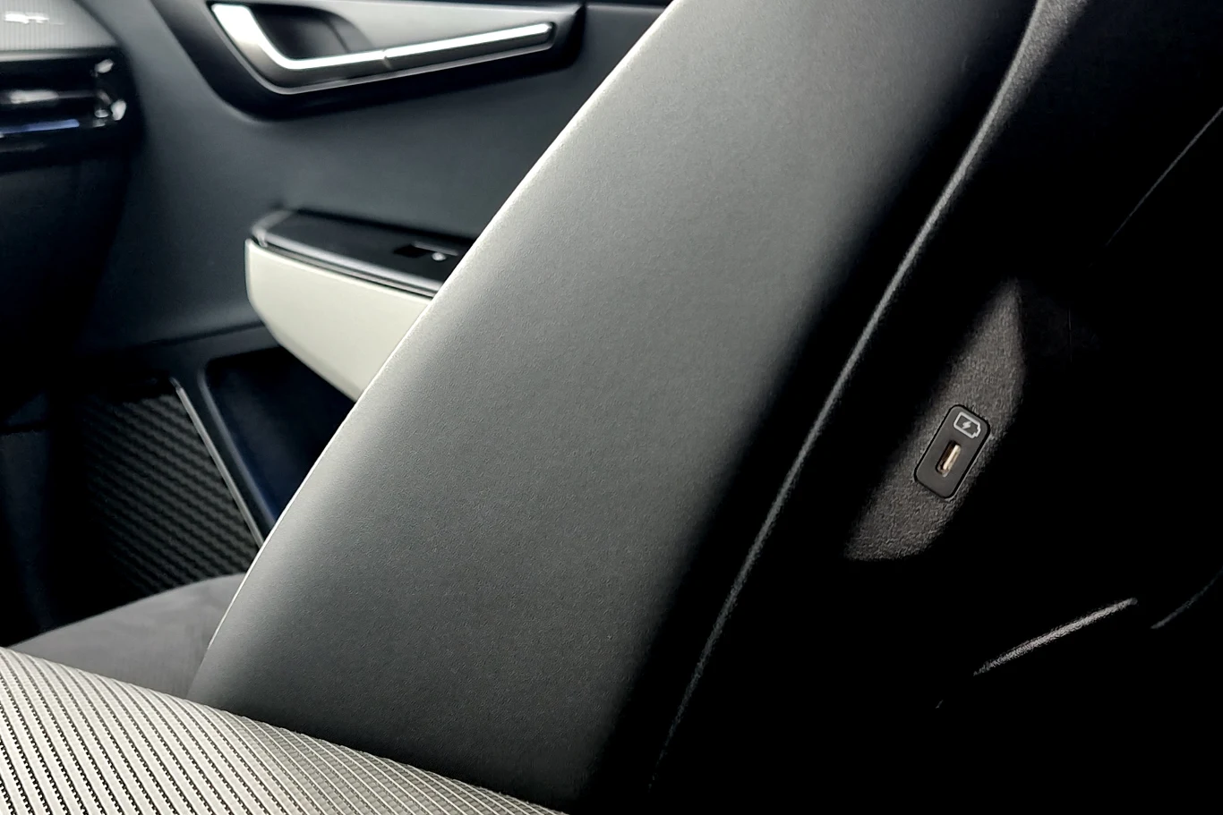 Nowoczesne wnętrze samochodu z widocznym podłokietnikiem, guzik do regulacji siedzenia oraz eleganckie wykończenie drzwi i panelu bocznego.