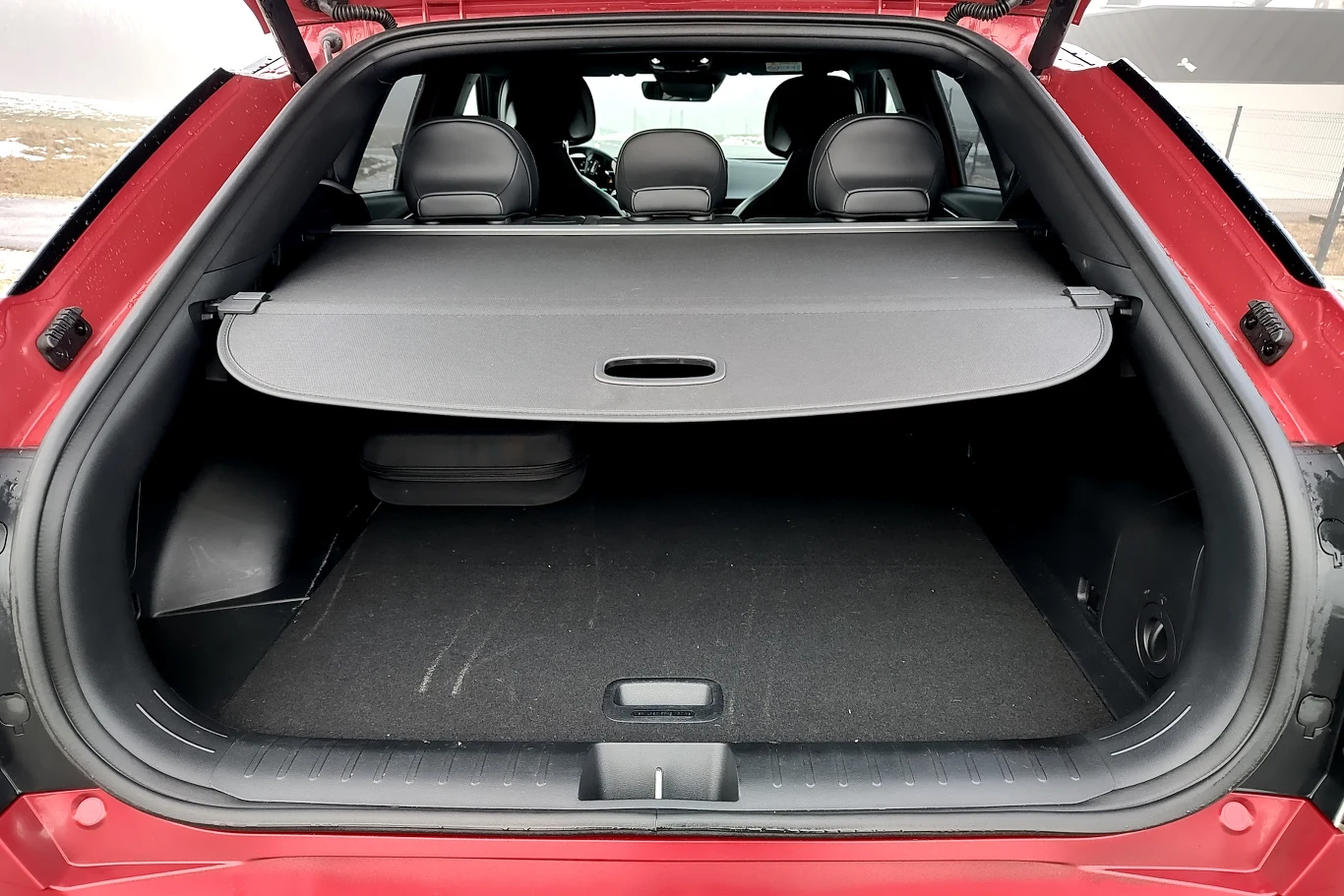 Przestronny bagażnik samochodu osobowego z rozłożoną roletą, trójrzędowe siedzenia widoczne przez otwartą klapę