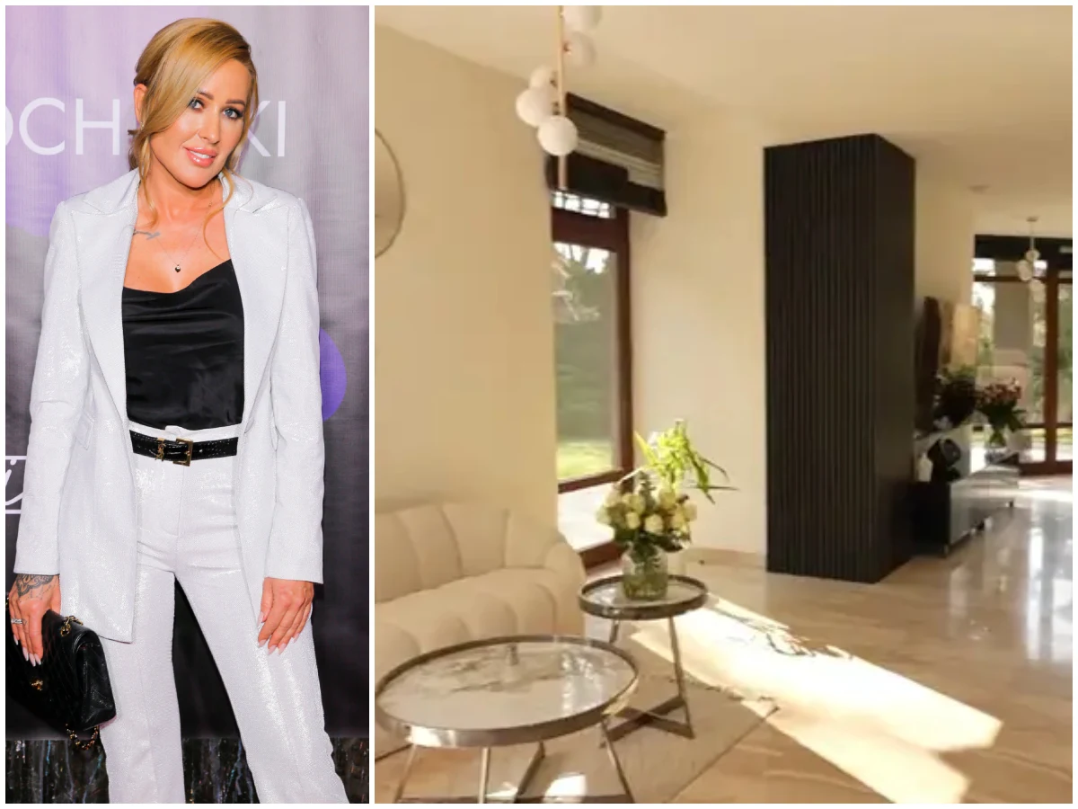 Elegancka kobieta w białym garniturze na tle jasnego pomieszczenia z dużymi oknami, białą sofą oraz okrągłymi stolikami, dekorowanego kwiatami w wazonach.