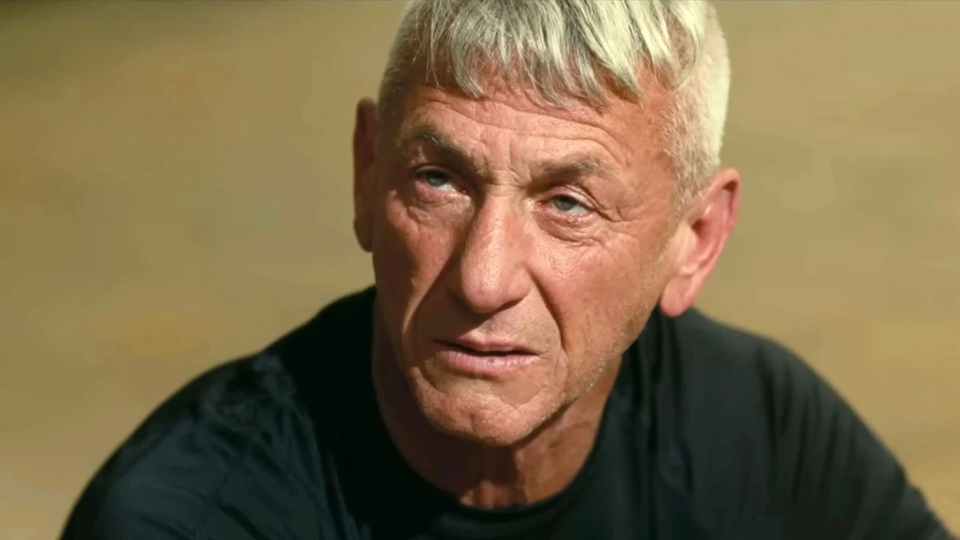 Starszy mężczyzna o krótkich, siwych włosach i skupionym wyrazie twarzy patrzący lekko w bok, ubrany w czarną koszulkę.