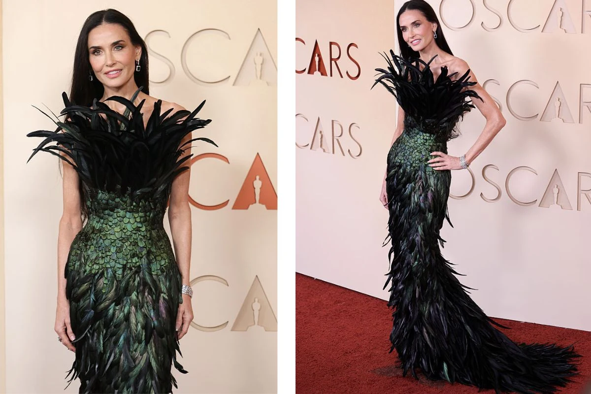 Kobieta w efektownej, zielono-czarnej sukni ozdobionej dużą ilością piór, stojąca na czerwonym dywanie na tle napisu 'Oscars'.