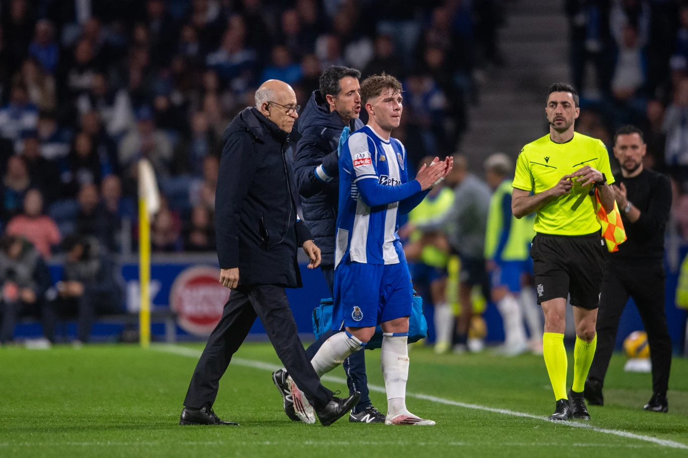 Oskar Pietuszewski opuszcza boisko w stroju FC Porto, obok sztab medyczny i sędzia w żółtym stroju.