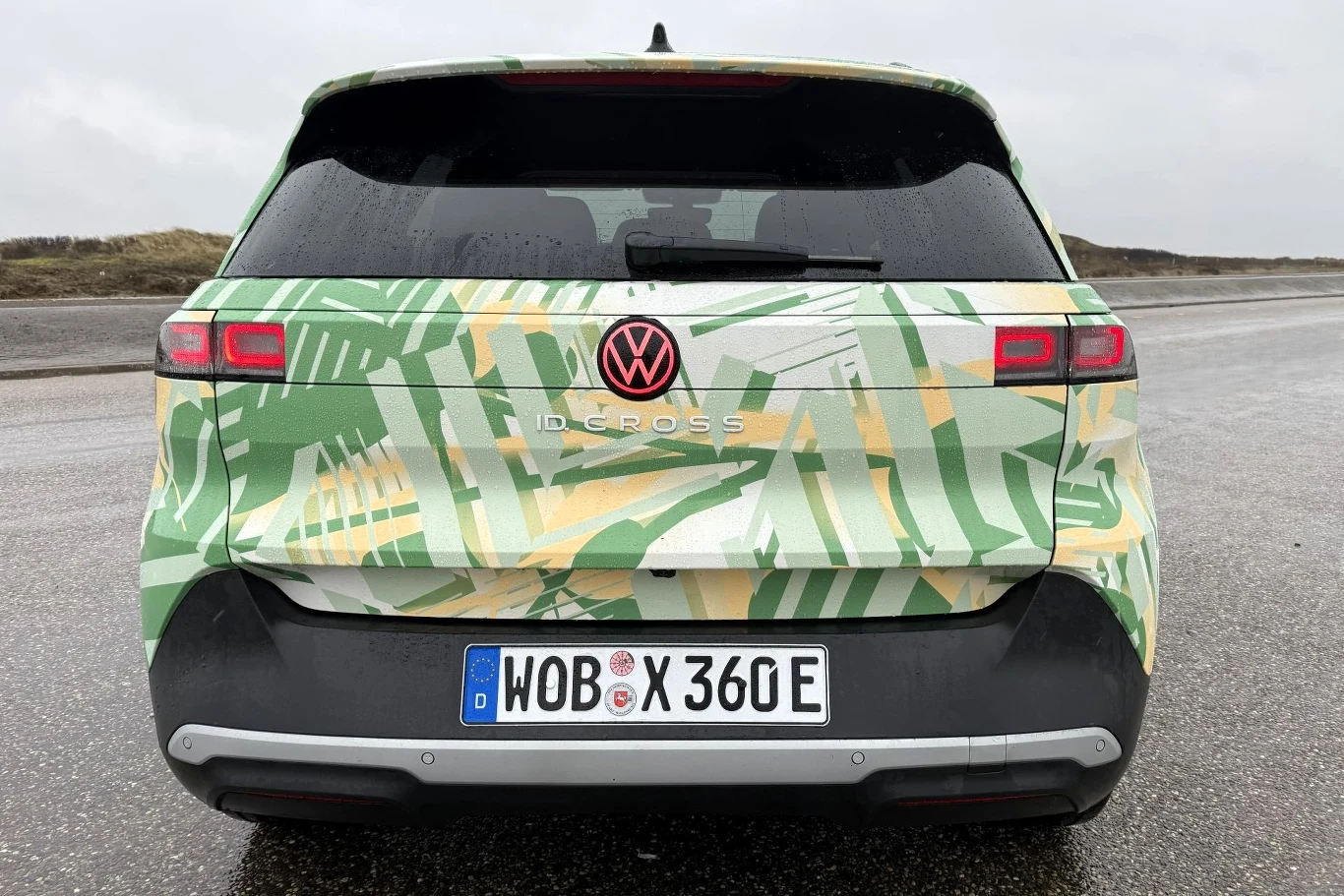 Tył samochodu Volkswagen ID.CROSS pokryty zielono-żółtym wzorem maskującym, wyraźne logo marki, tylne reflektory LED oraz niemiecka tablica rejestracyjna.