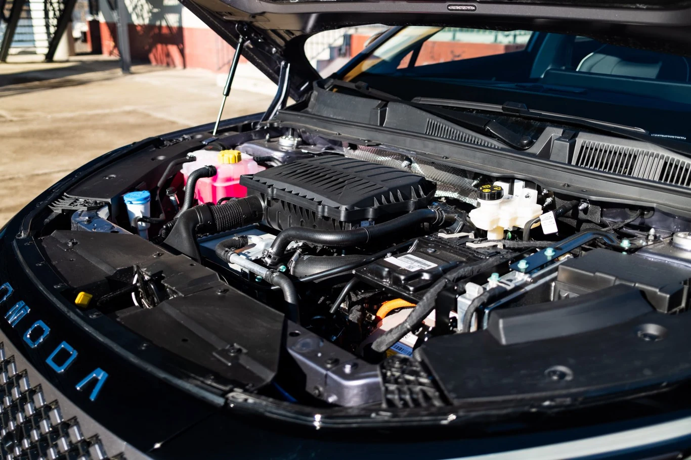 otwarta maska samochodu ukazująca nowoczesny silnik z elementami układu chłodzenia i zbiornikami płynów eksploatacyjnych w dobrze utrzymanej komorze silnika